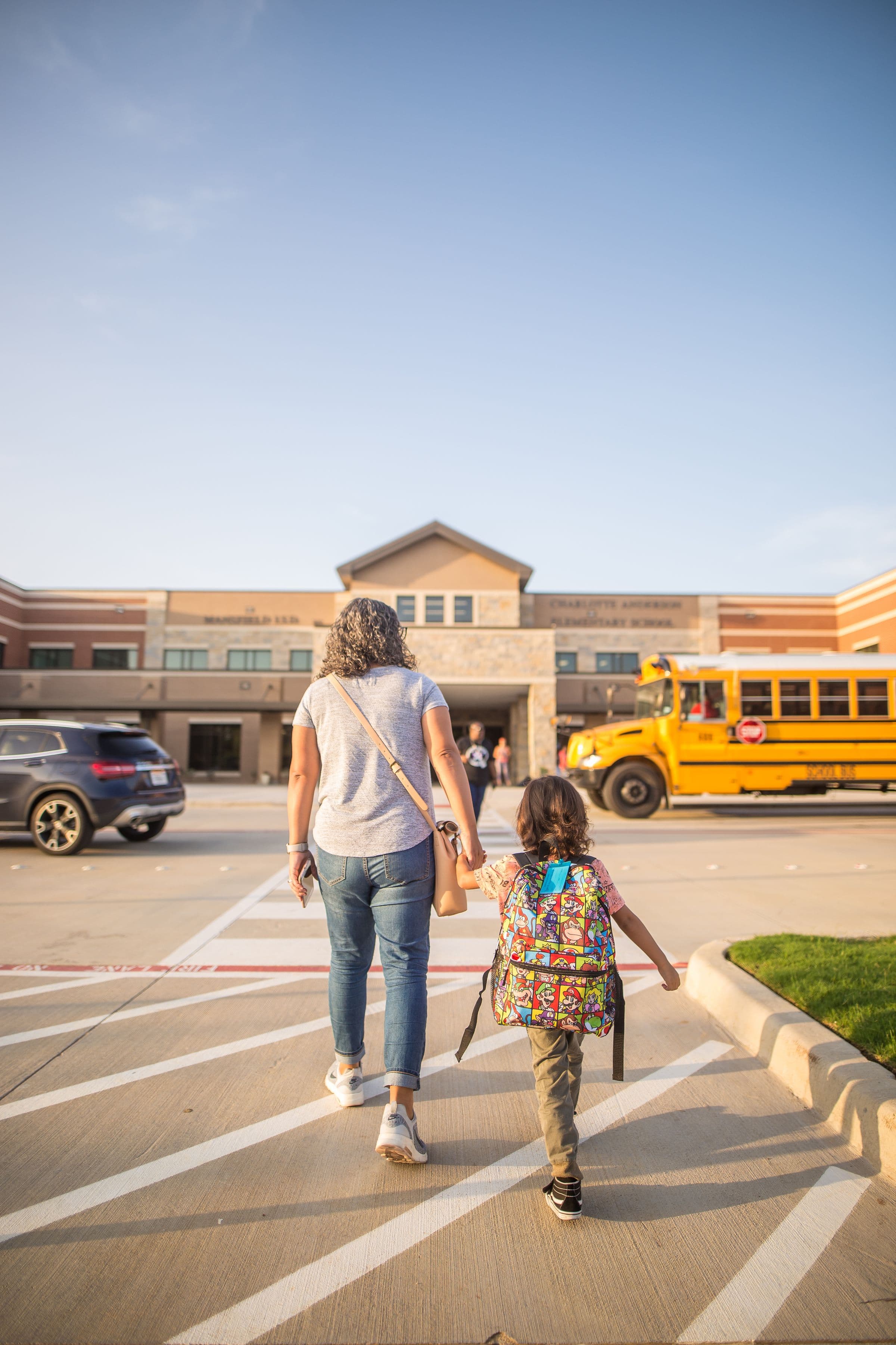 A parent walking their child to school at golden hour
