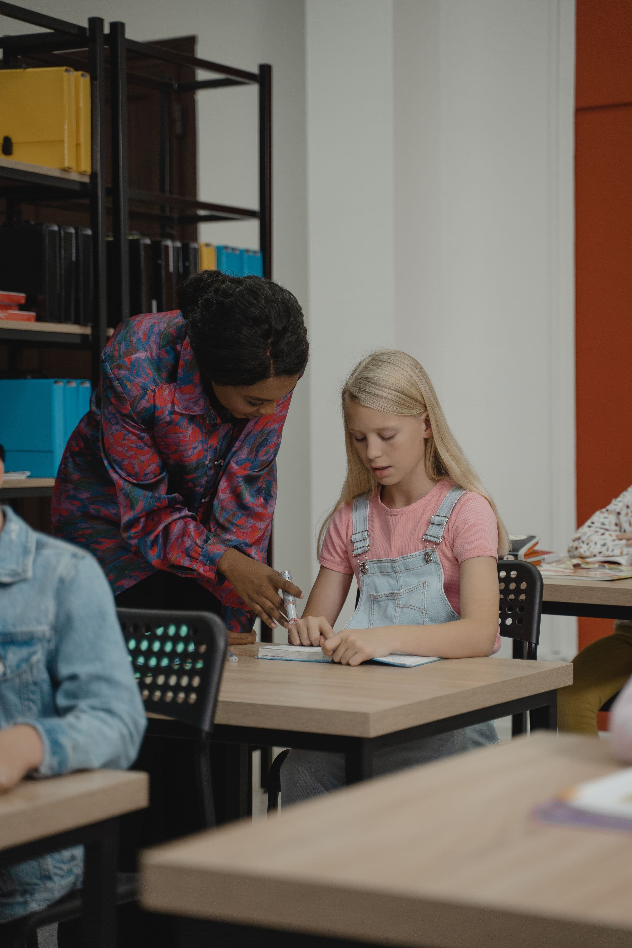 A teacher supporting a student at her desk